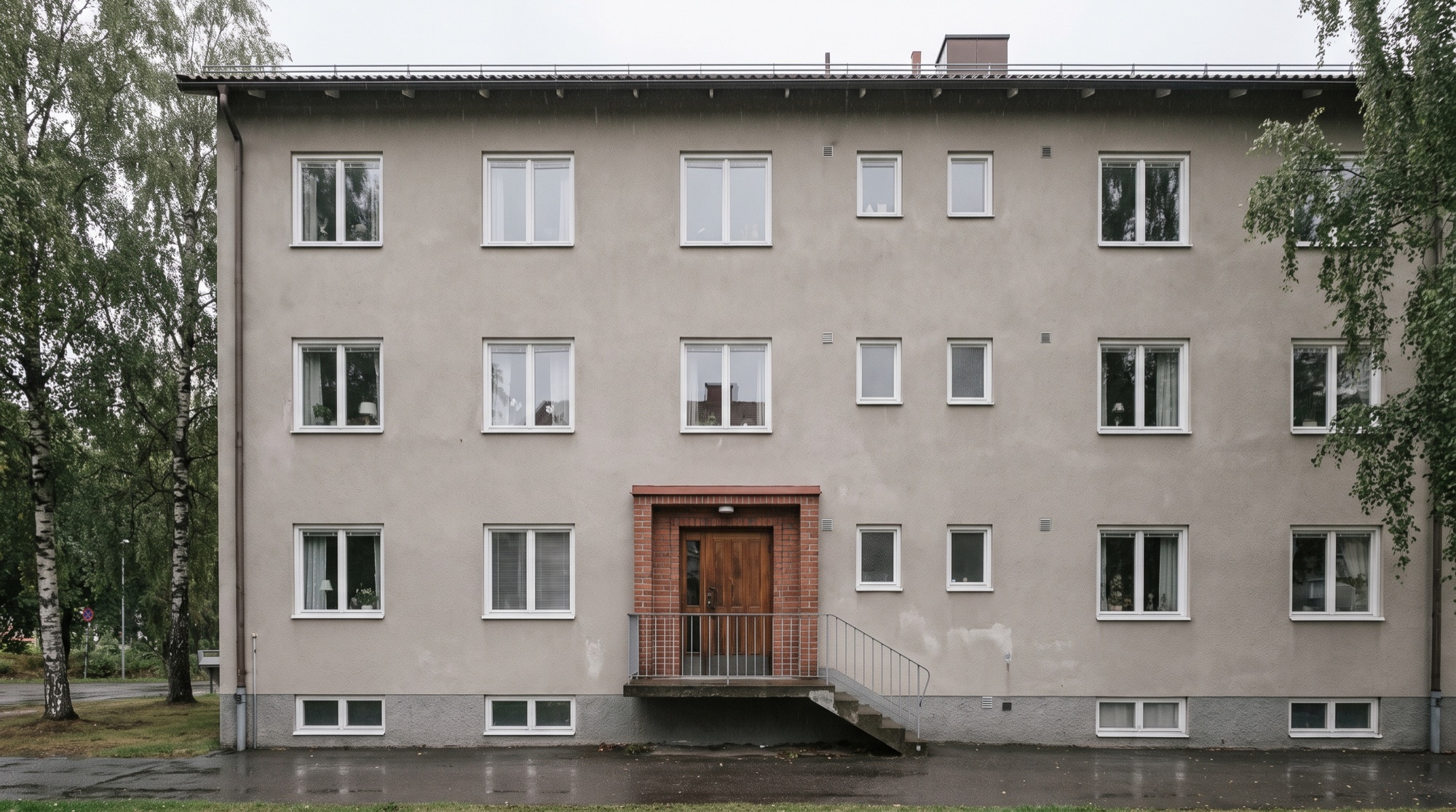 Flerbostadshus från 1960-talet med tegelinramad entré och trappa